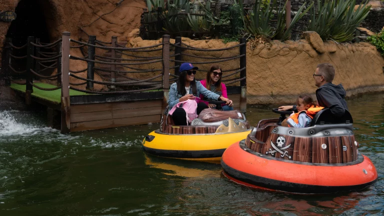 Families enjoying bumper boats ride at a theme park water attraction.
