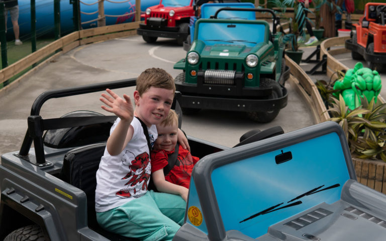 Children enjoying a ride on colourful mini jeeps at an amusement park.