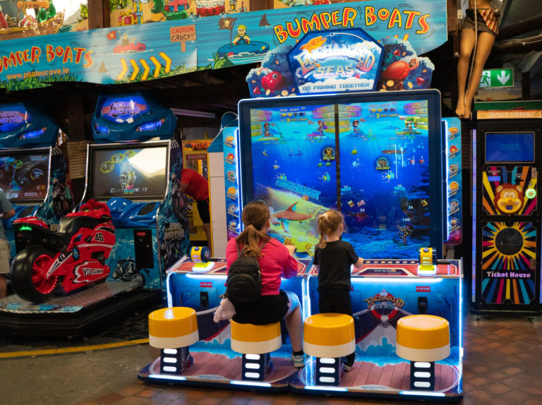Children playing arcade fishing game in a lively amusement arcade.
