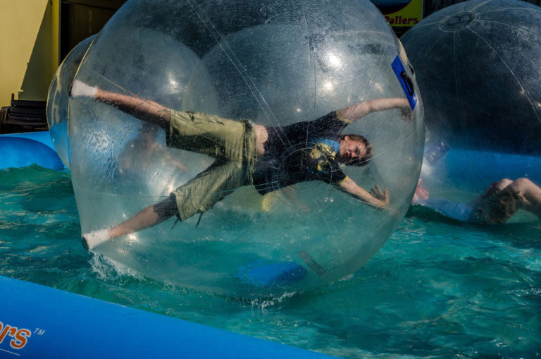 Person inside inflatable pool ball on water.