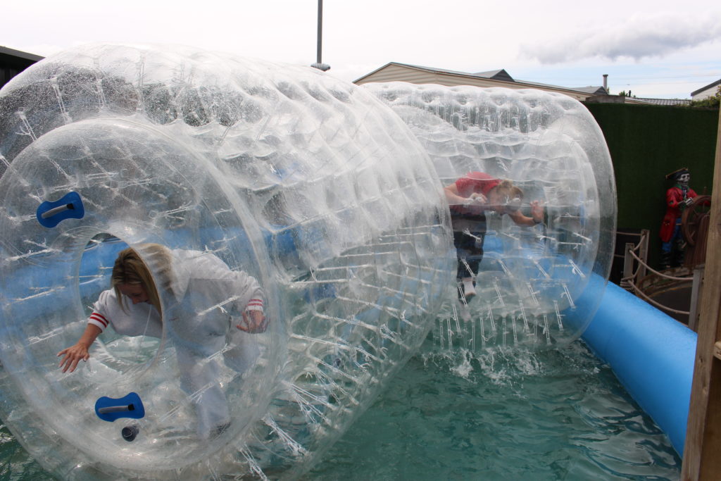People enjoying water zorbing fun in inflatable hamster wheels.