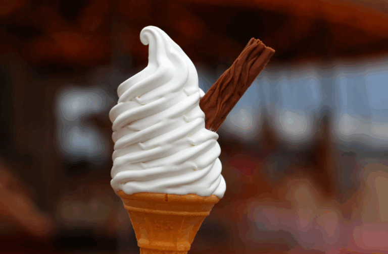 Soft serve ice cream cone with a chocolate flake on a sunny day.