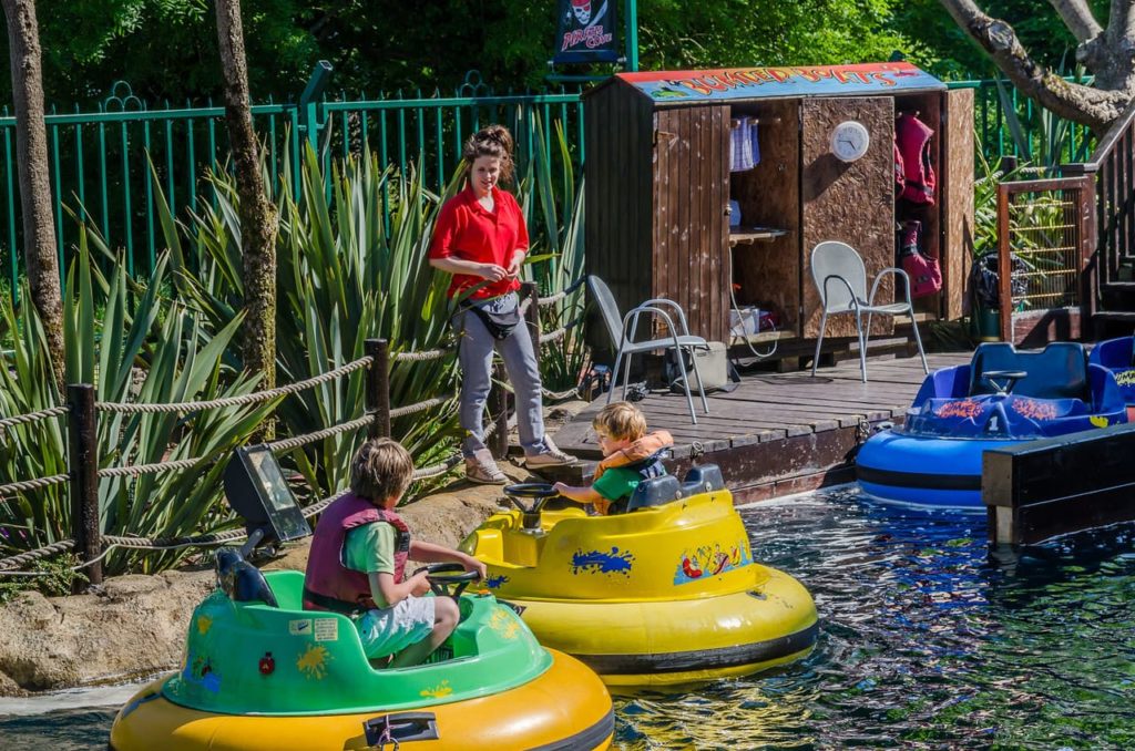 Children enjoying bumper boats at a sunny amusement park.