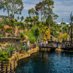 Tropical adventure golf course with pirate ship and lush greenery.