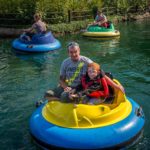 Father and child on a sunny day in colourful bumper boats at an amusement park.