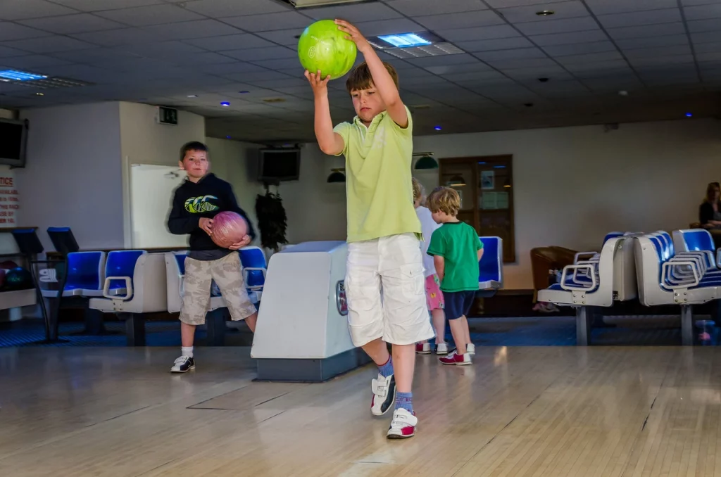 Children playing bowling in a brightly-lit alley, with colourful balls and excitement.